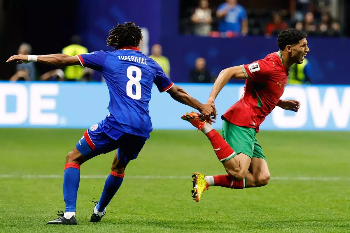 Morocco's Achraf Hakimi, right, falls as he competes against Haiti's Martin Experience (8) during the World Cup Group C soccer match between Morocco and Haiti in Atlanta, Wednesday, June 24, 2026. (AP Photo/Erik S. Lesser)