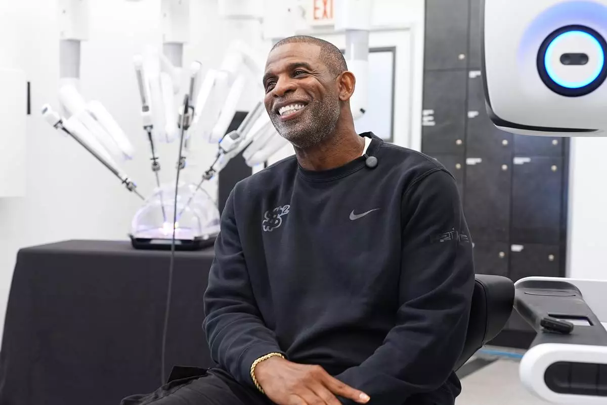 Colorado head football coach Deion Sanders talks about working the Da Vinci robotic surgical machine used to remove his cancerous bladder last year during a demonstration of the device Tuesday, June 23, 2026, in Boulder, Colo. (AP Photo/David Zalubowski)