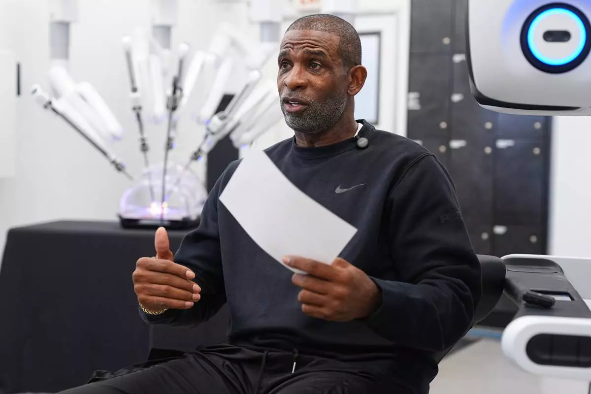 Colorado head football coach Deion Sanders talks after working the Da Vinci robotic surgical machine used to remove his cancerous bladder last year during a demonstration of the device Tuesday, June 23, 2026, in Boulder, Colo. (AP Photo/David Zalubowski)
