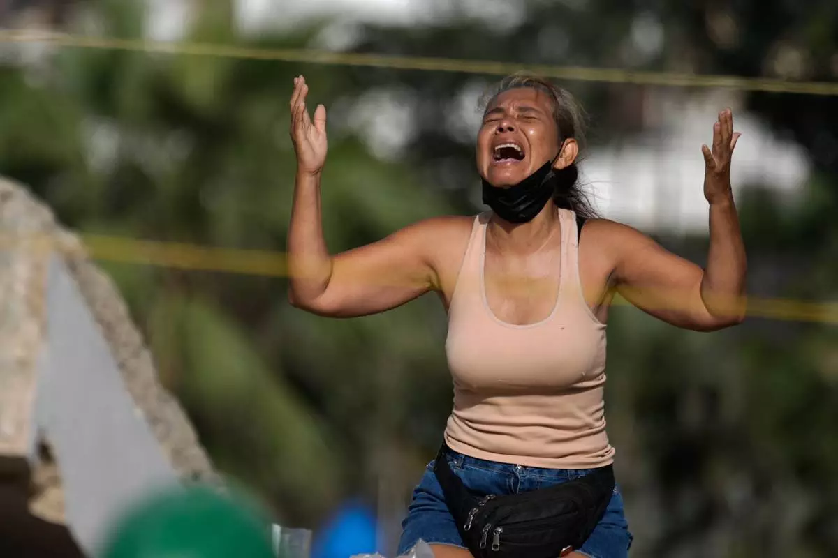 FILE - Carolina Munoz prays as she searches for the body of her son, Carlos Munoz, in the debris of a building collapsed by an earthquake in La Guaira, Venezuela, July 15, 2026. (AP Photo/Ariana Cubillos, File)