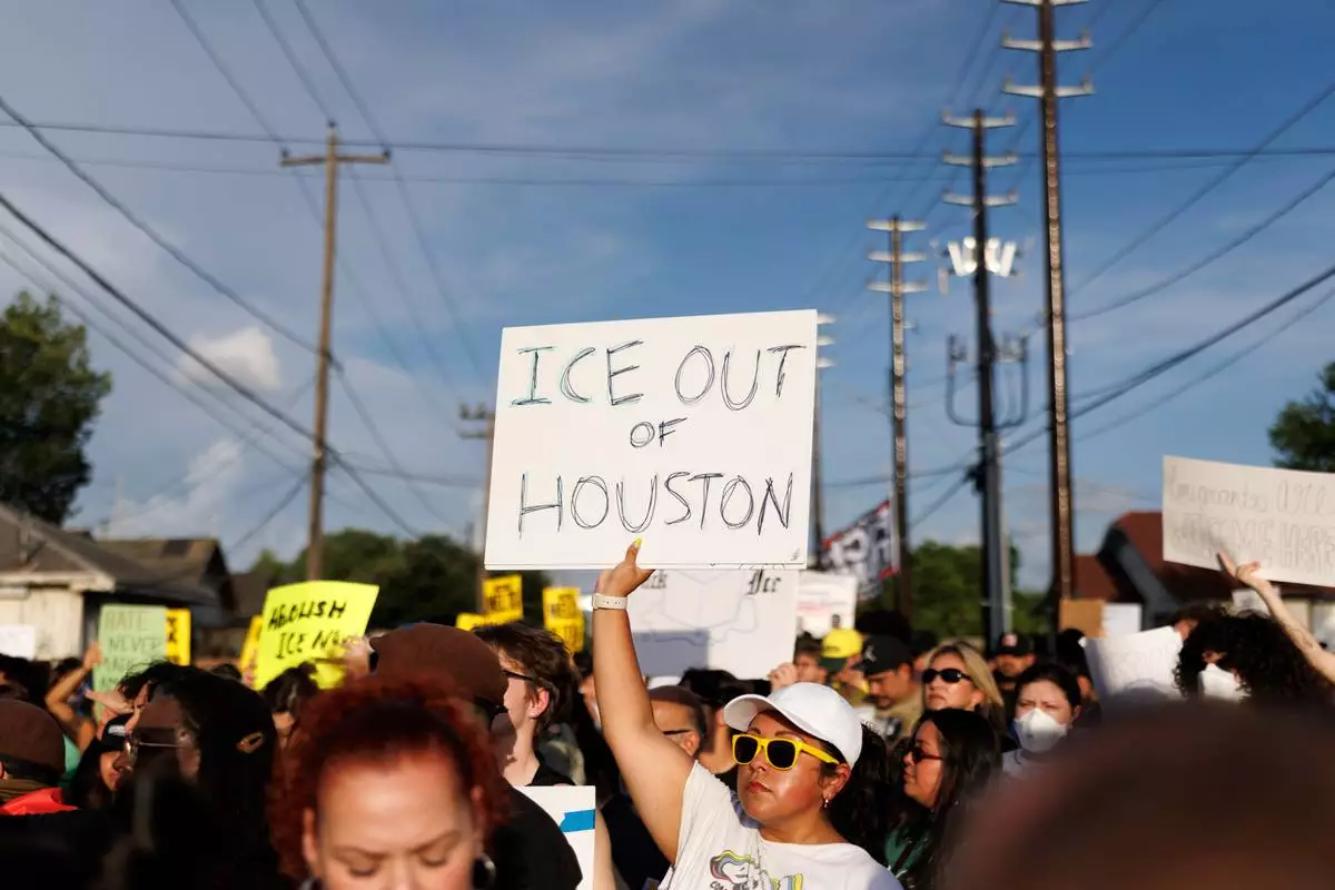A woman holds a sign reading "ICE OUT OF HOUSTON" during a vigil for Lorenzo Salgado Araujo, a Mexican national fatally shot by a federal immigration agent a day prior, Wednesday, July 8, 2026, in Houston. (AP Photo/Mark Felix)