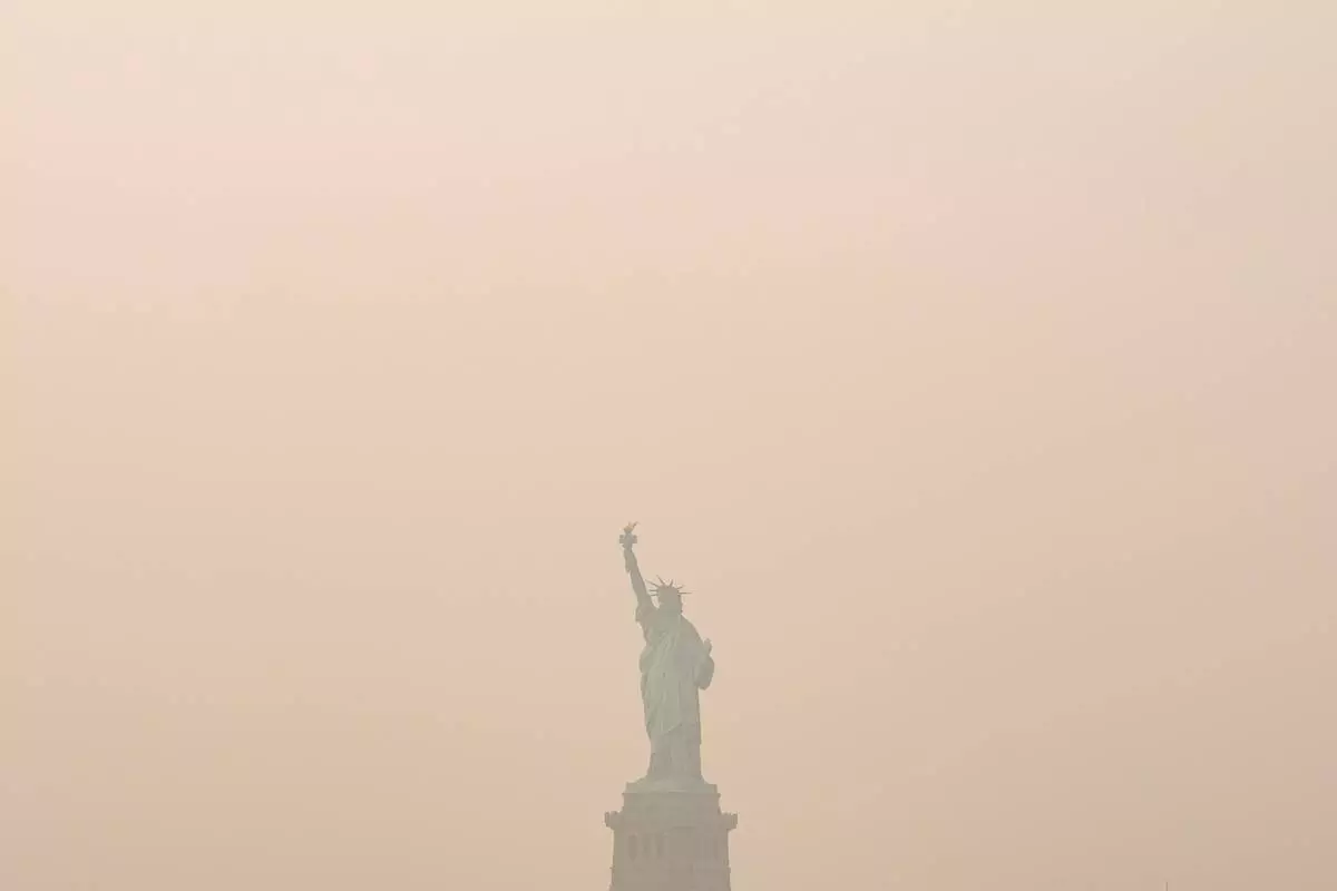 The Statue of Liberty is photographed from the Staten Island Ferry as smoke from wildfires blankets the sky, Thursday, July 16, 2026, in New York. (AP Photo/Yuki Iwamura)