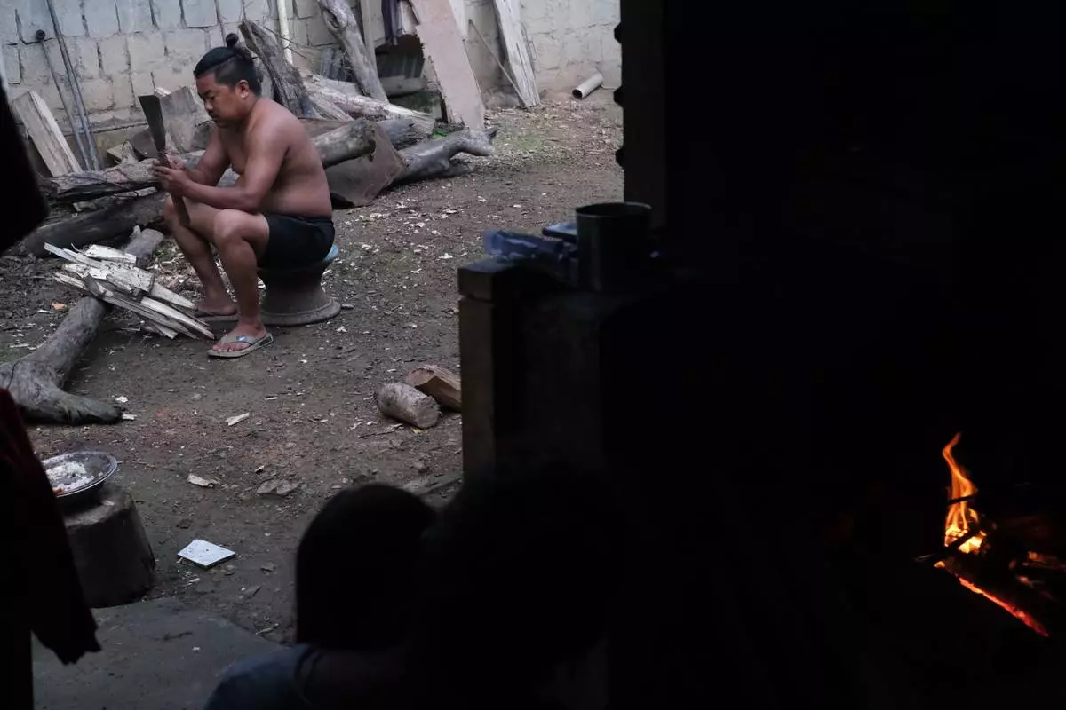 Tovi Murru, 32, chops wood to cook dinner in Kohima, capital of the northeastern Indian state of Nagaland, Monday, July 6, 2026. (AP Photo/Yirmiyan Arthur)