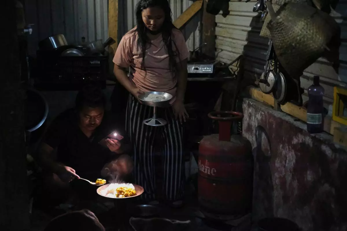 Tovi Murru, 32, and his wife Atoshi Ayemi serve food beside an empty liquefied petroleum gas cylinder inside their kitchen in Kohima, capital of the northeastern Indian state of Nagaland, Monday, July 6, 2026. (AP Photo/Yirmiyan Arthur)