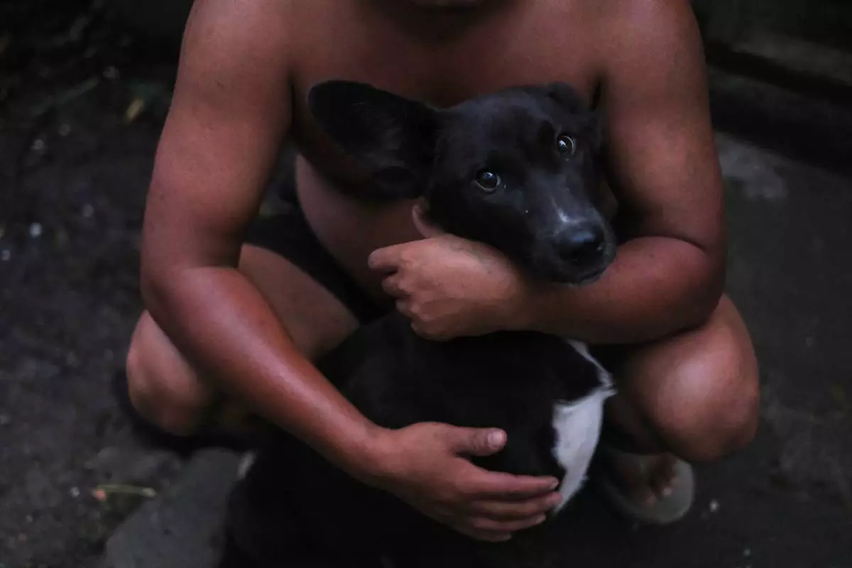 Tovi Murru, 32, puts his arms around his pet dog outside his house in Kohima, capital of the northeastern Indian state of Nagaland, Monday, July 6, 2026. (AP Photo/Yirmiyan Arthur)