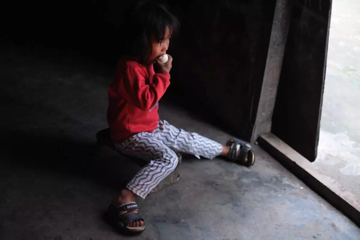 Azatina Murru, 3, eats an egg by the entrance of her home in Kohima, capital of the northeastern Indian state of Nagaland, Monday, July 6, 2026. (AP Photo/Yirmiyan Arthur)