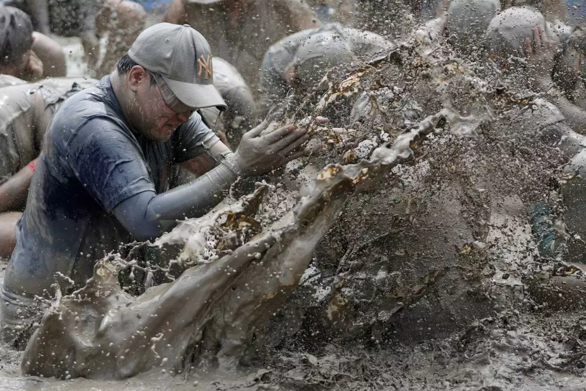 A participant plays in a mud pool during the Boryeong mud festival near a beach in Boryeong, South Korea, Saturday, July 25, 2026. (AP Photo/Lee Jin-man)