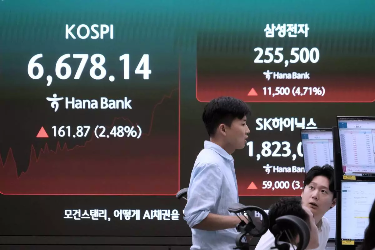 Currency traders work near a screen showing the Korea Composite Stock Price Index (KOSPI), SK Hynix and Samsung Electronics Co. stock price at the foreign exchange dealing room of the Hana Bank headquarters in Seoul, South Korea, Tuesday, July 21, 2026. (AP Photo/Ahn Young-joon)
