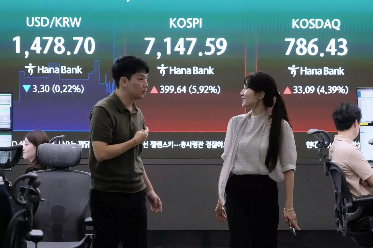 Currency traders work near a screen showing the Korea Composite Stock Price Index (KOSPI) and the foreign exchange rate between U.S. dollar and South Korean won at the foreign exchange dealing room of the Hana Bank headquarters in Seoul, South Korea, Wednesday, July 22, 2026. (AP Photo/Ahn Young-joon)