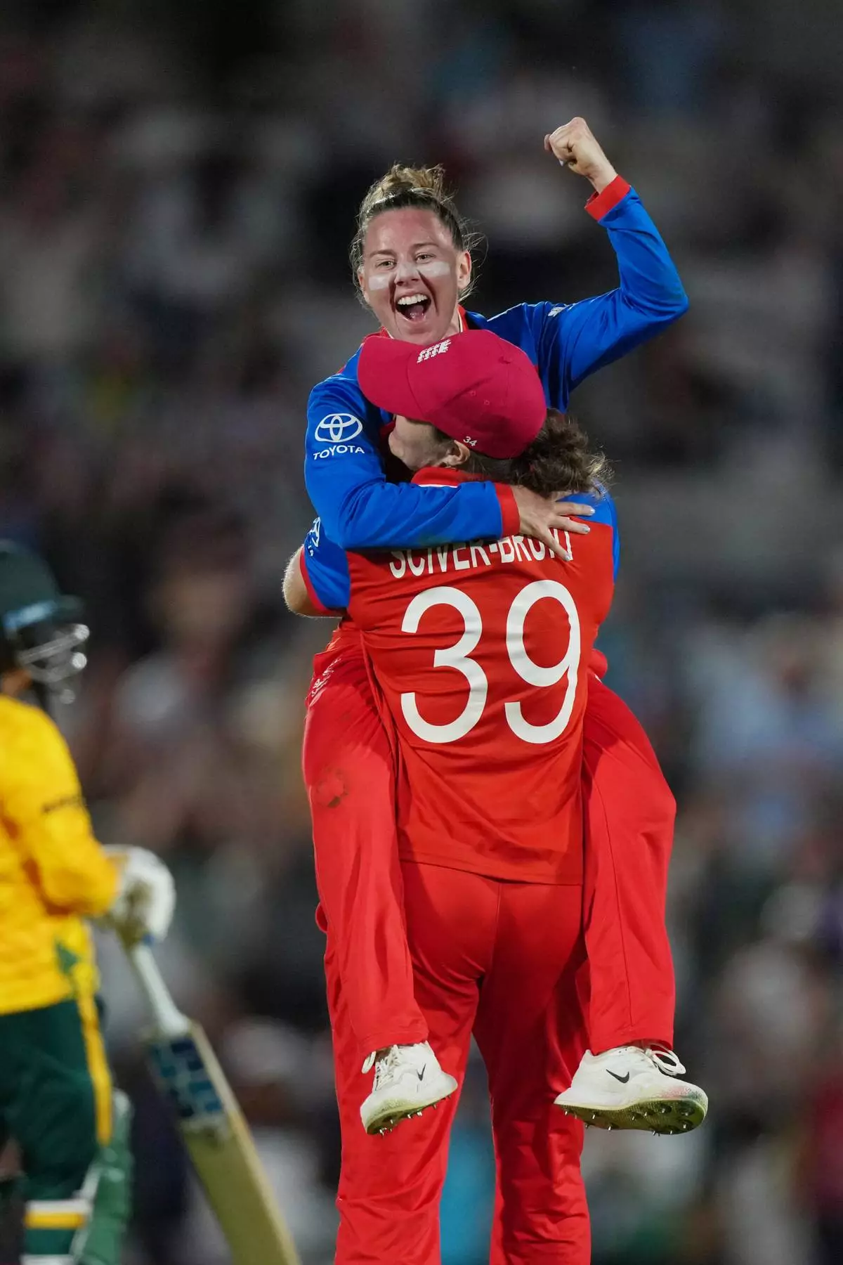 England's Sophie Ecclestone, back to the camera, celebrates with Linsey Smith, top, after winning the Women's T20 Cricket World Cup semifinal match between England and South Africa in London, Thursday, July 2, 2026. (AP Photo/Alastair Grant)