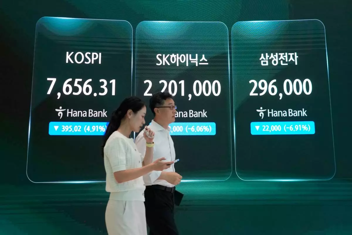 Currency traders pass by a screen showing the Korea Composite Stock Price Index (KOSPI), left, SK Hynix and Samsung Electronics Co., right, stock price at the foreign exchange dealing room of the Hana Bank headquarters in Seoul, South Korea, Tuesday, July 7, 2026. (AP Photo/Ahn Young-joon)