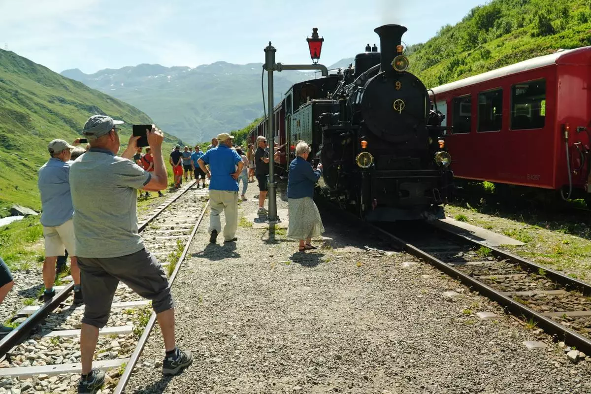 Passengers take photos during a train stop to refill the locomotive with water at Tiefenbach station near Realp, Switzerland, Friday, June 26, 2026. (AP Photo/Niccolo Lupone)