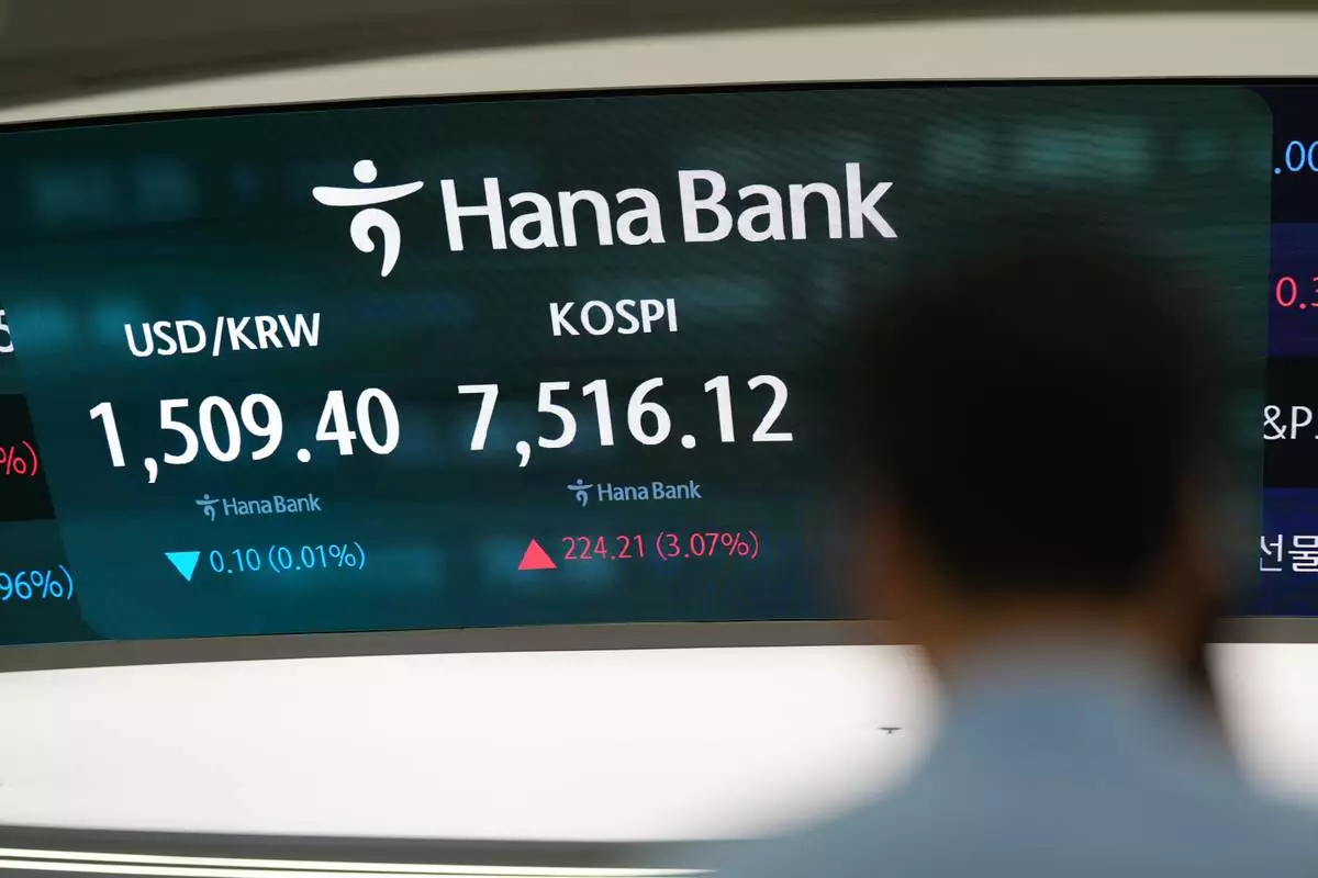 A dealer walks past near the screens showing the Korea Composite Stock Price Index (KOSPI) and the foreign exchange rate between U.S. dollar and South Korean won at a dealing room of Hana Bank in Seoul, South Korea, Friday, July 10, 2026. (AP Photo/Lee Jin-man)