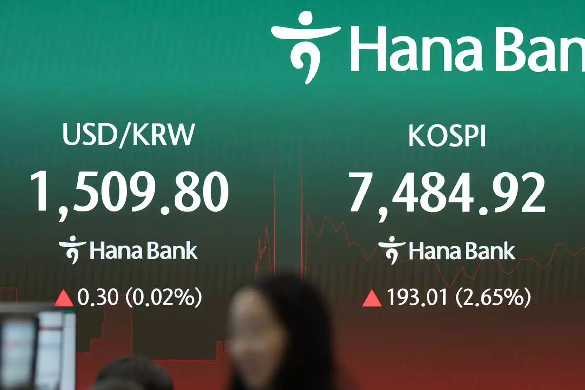 A dealer walks past near the screens showing the Korea Composite Stock Price Index (KOSPI) and the foreign exchange rate between U.S. dollar and South Korean won at a dealing room of Hana Bank in Seoul, South Korea, Friday, July 10, 2026. (AP Photo/Lee Jin-man)