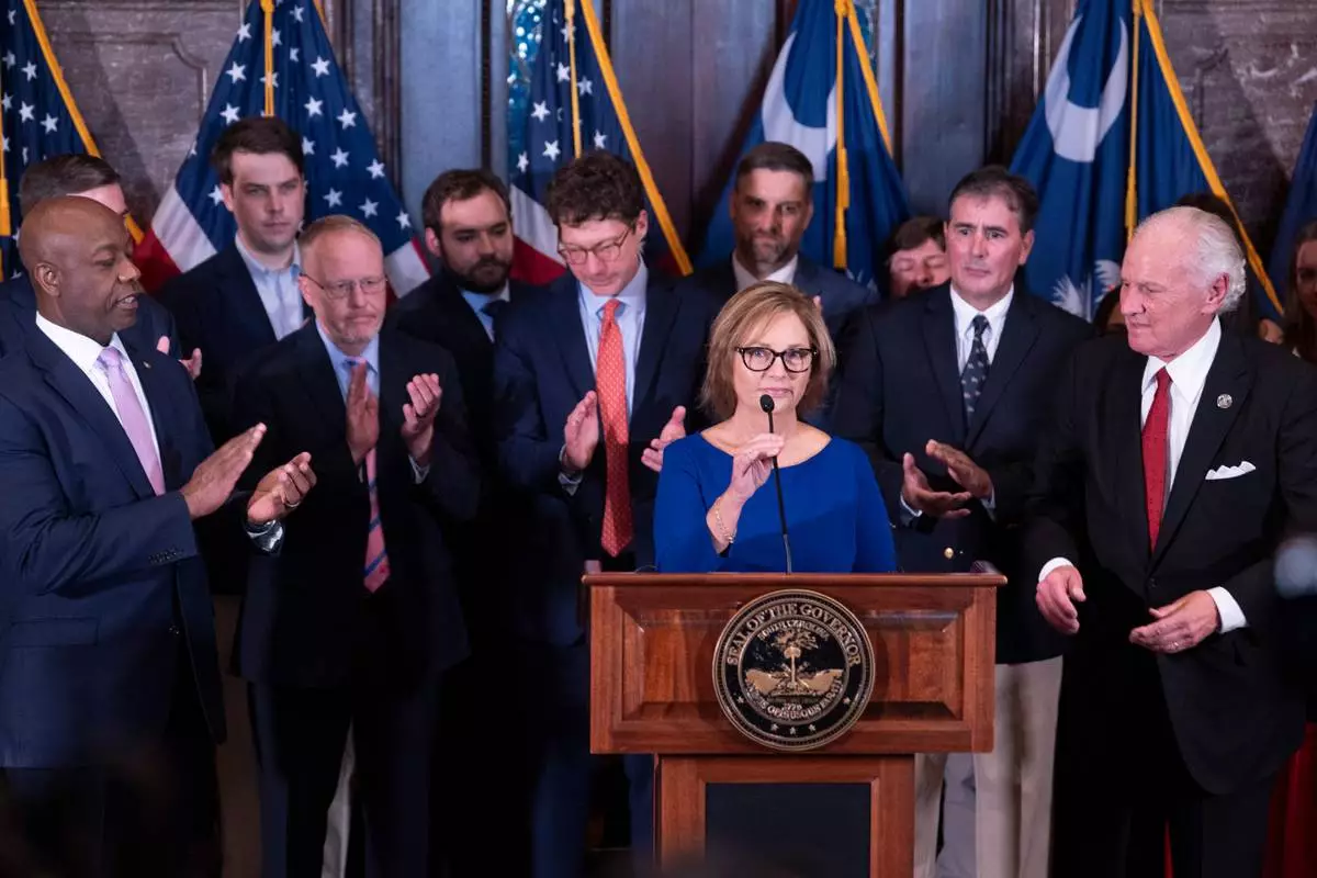 Newly appointed U.S. interim Senator, Darline Graham Nordone, with South Carolina Gov. Henry McMaster, right, and Sen. Tim Scott (R-SC), left, speaks to members of the press after being appointed to fill the vacancy created by the passing of her brother, U.S. Senator Lindsey Graham, at the statehouse Monday, July 13, 2026, in Columbia, S.C. (AP Photo/Sean Rayford) CORRECTION: Corrects senator Scott's first name.