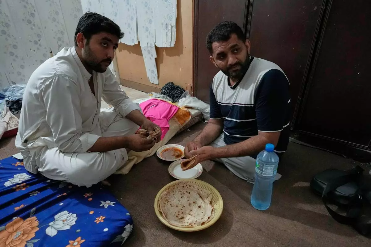Hamza Ali, 28, who lost both legs in a road accident, eats a meal with his cousin, Mohammad Aftab, in his room in Islamabad, Pakistan, Tuesday, July 21, 2026. (AP Photo/Anjum Naveed)
