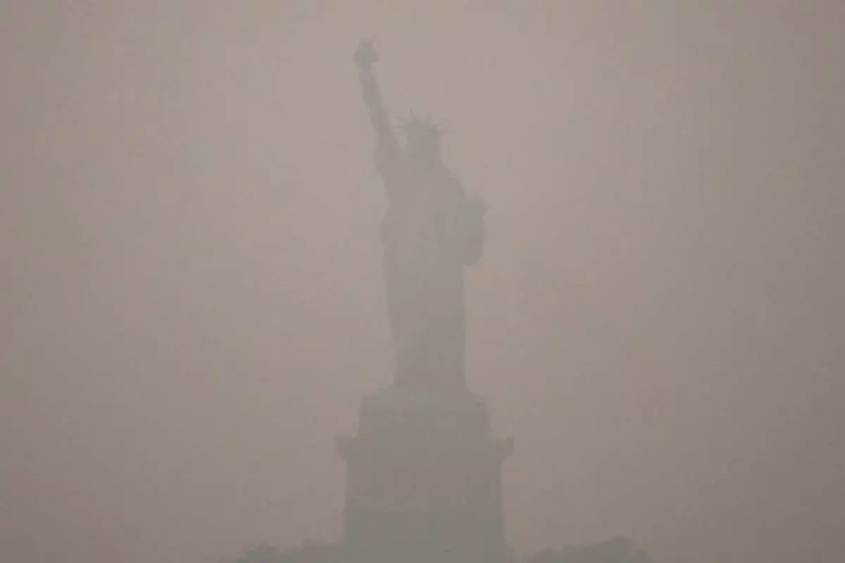 The Statue of Liberty stands during sunset as smoke from wildfires blankets the sky, Thursday, July 16, 2026, in the Brooklyn borough of New York. (AP Photo/Yuki Iwamura)
