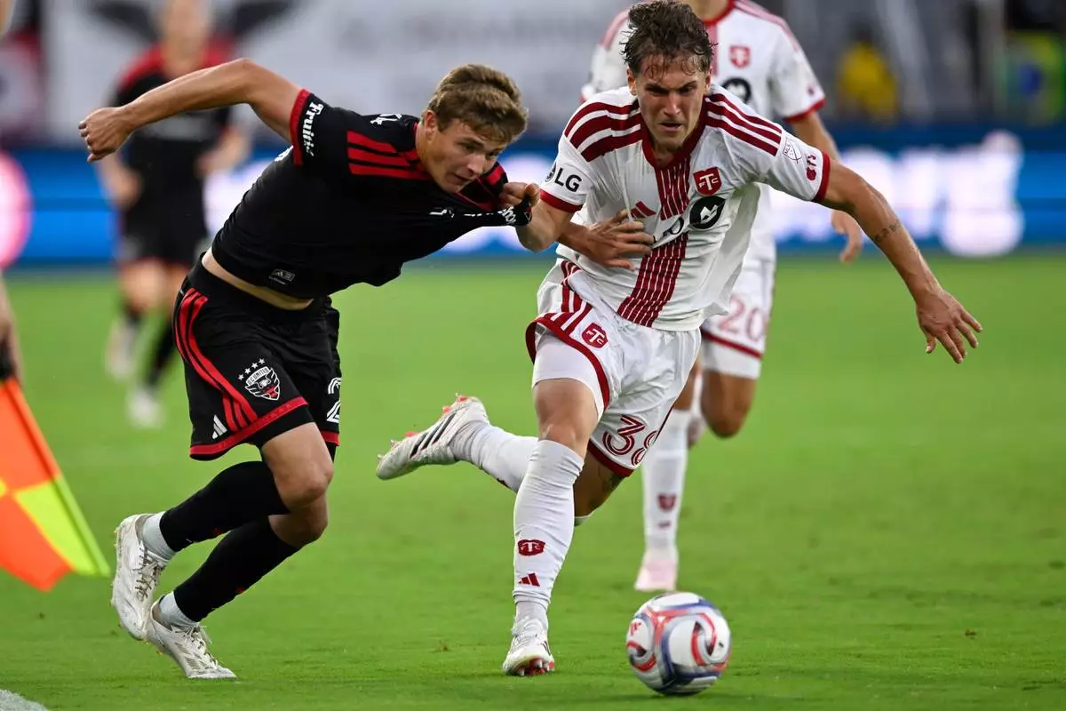 D.C. United midfield Jackson Hopkins, left, and Toronto FC defense Jackson Gilman, right, compete for the ball during the first half of an MLS soccer match, Saturday, July 25, 2026, in Washington. (AP Photo/John McDonnell)