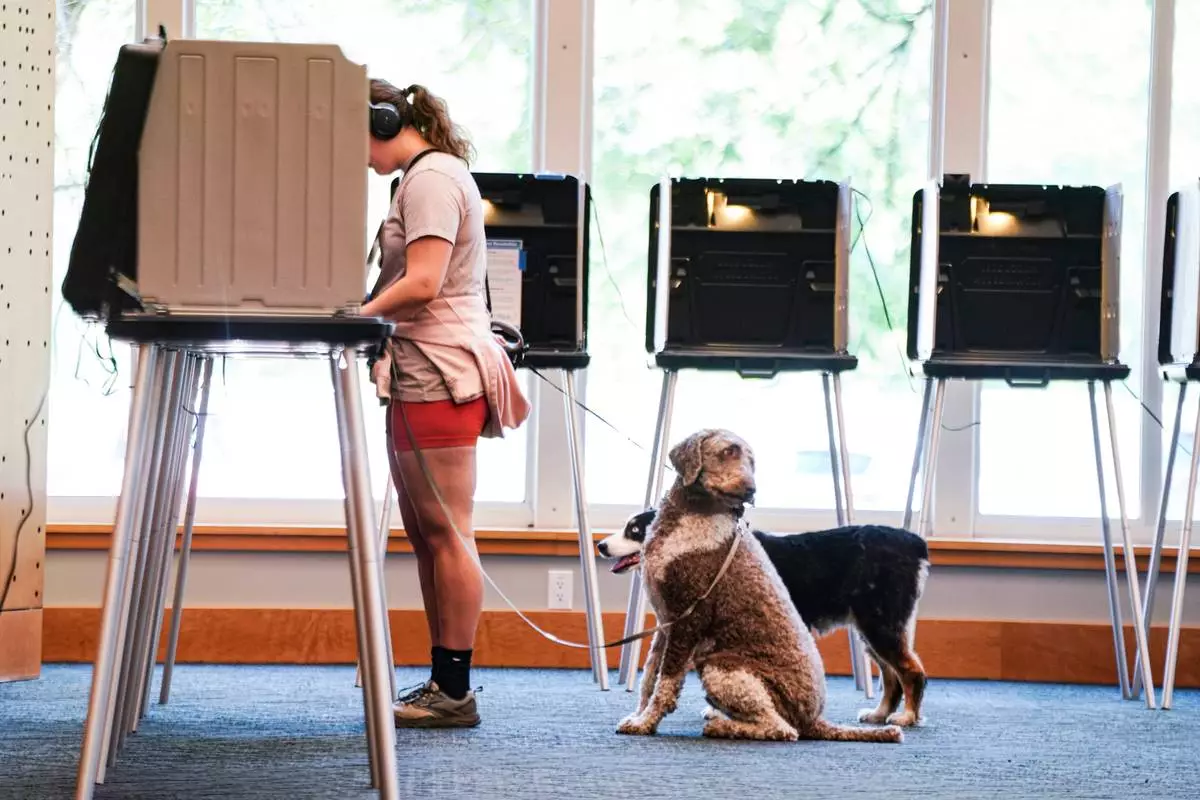 Danielle Grisolano brings her dogs Lincoln and Pepper with her to vote in the Democratic primaries at Denver Public Library, Tuesday, June 30, 2026, in Denver. (AP Photo/Rebecca Slezak)