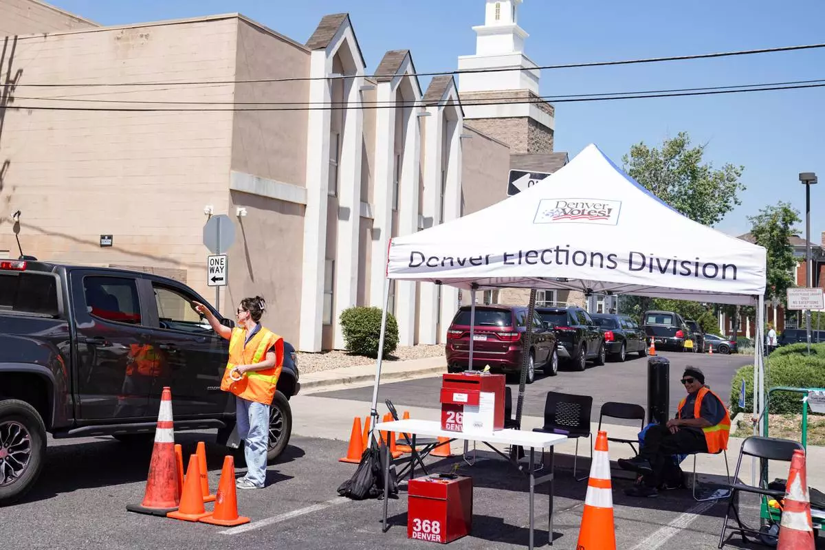 Erin Ludlam talks to a voter about where they can park and vote inside of Blair-Caldwell Library, Tuesday, June 30, 2026, in Denver. (AP Photo/Rebecca Slezak)