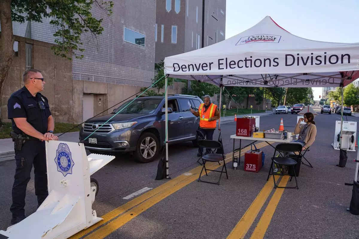 Adam Ballinger walks a voters ballot to the box in the Democratic primaries at a drop off location near the Denver Museum of Art, Tuesday, June 30, 2026, in Denver. (AP Photo/Rebecca Slezak)