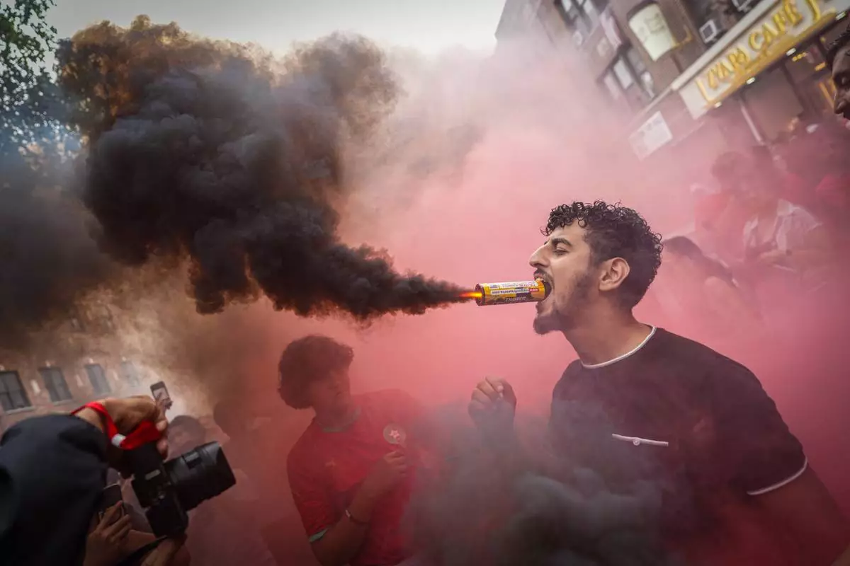 A Morocco fan holds a flare in his mouth after the team lost the World Cup quarterfinal soccer match between France and Morocco, Thursday, July 9, 2026, in the Queens borough of New York. (AP Photo/Ryan Murphy)