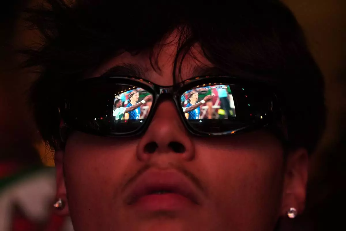 Croatia's team captain Luka Modric is reflected on the glasses of a Portugal fan watching on a big screen in Lisbon, Portugal, the World Cup round of 32 soccer match between Portugal and Croatia, Friday, July 3, 2026. (AP Photo/Armando Franca)