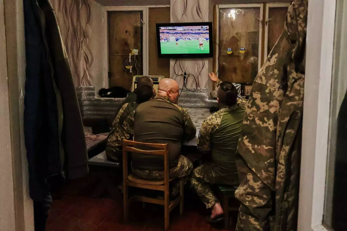 In this photo provided by Ukraine's 65th Mechanized Brigade press service, soldiers react as they watch a broadcast of the World Cup semifinal soccer match between France and Spain after after a mission on the frontline in the Zaporizhzhia region, Ukraine, Tuesday, July 14, 2026. (Andriy Andriyenko/Ukraine's 65th Mechanized Brigade via AP)