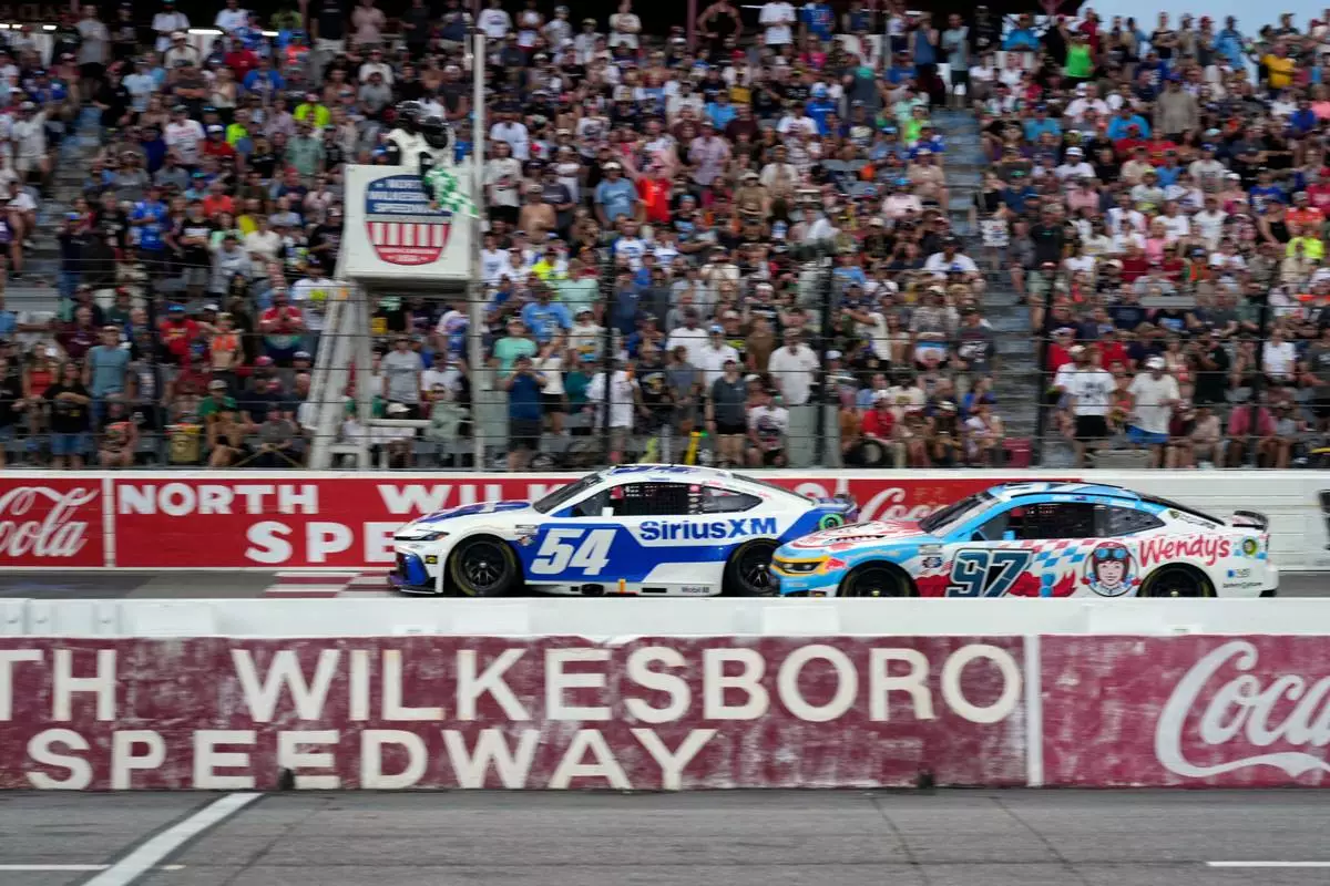 Ty Gibbs (54) passes Shane van Gisbergen (97) to win the first segment of a NASCAR Cup Series auto race in North Wilkesboro, N.C., Sunday, July 19, 2026. (AP Photo/Chuck Burton)