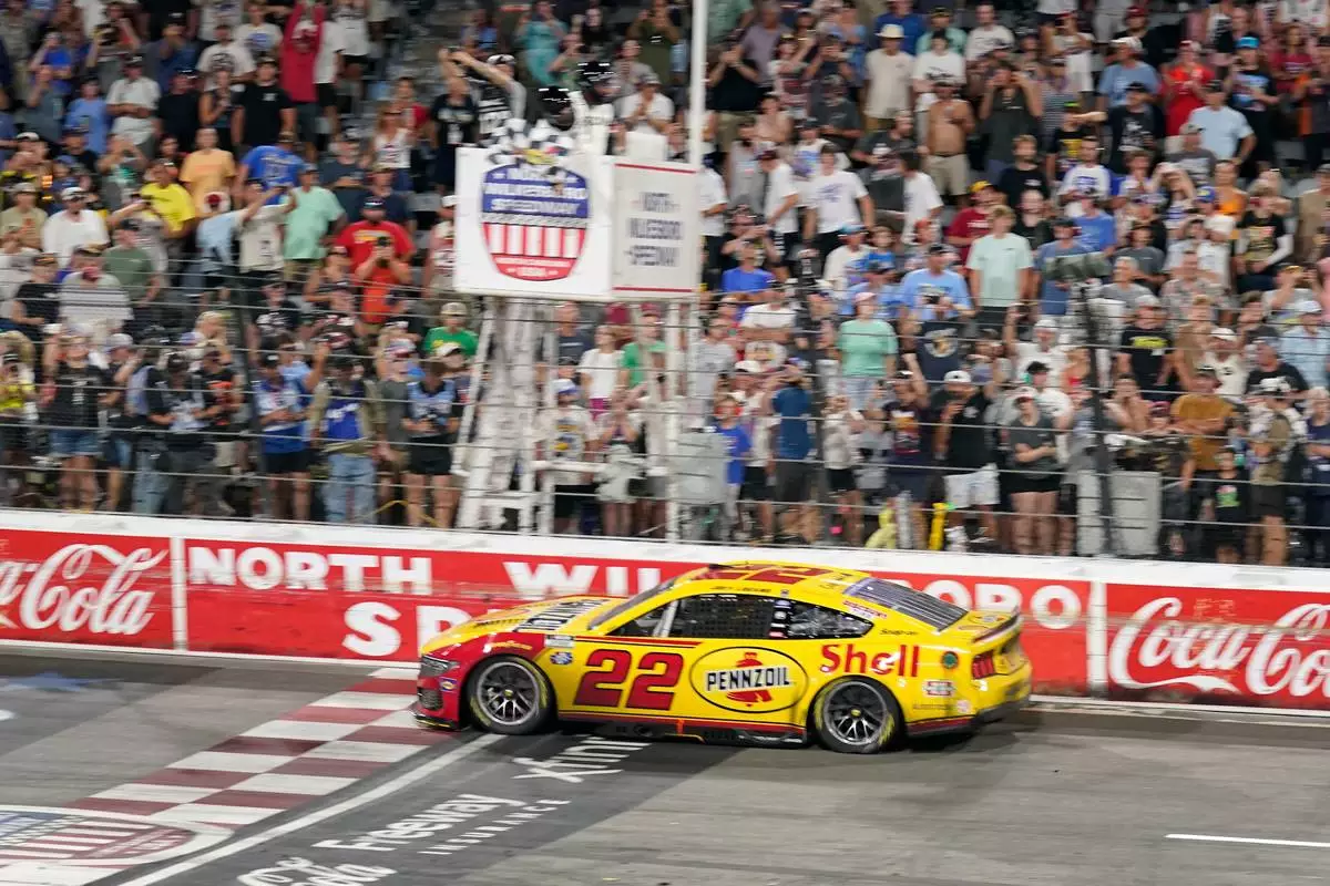Joey Logano (22) takes th checkered flag to win a NASCAR Cup Series auto race in North Wilkesboro, N.C., Sunday, July 19, 2026. (AP Photo/Chuck Burton)