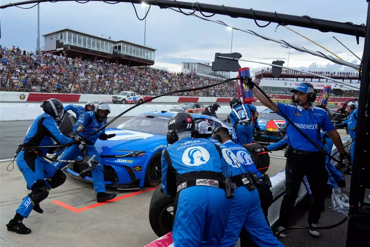 Crew members perform a pit stop on driver Denny Hamlin's car during a NASCAR Cup Series auto race in North Wilkesboro, N.C., Sunday, July 19, 2026. (AP Photo/Chuck Burton)