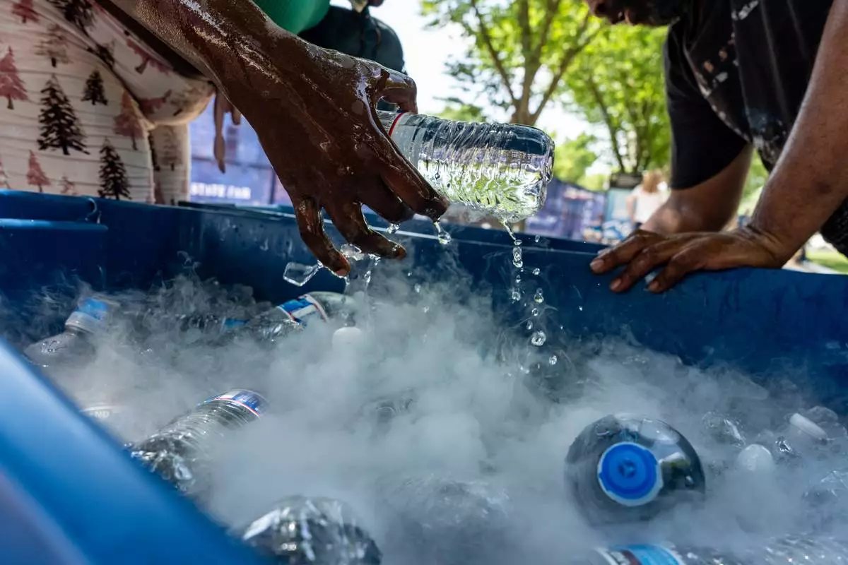 A vendor pulls out a bottle of water from a tank using dry ice to keep it cold, during a heat wave at the Great American State Fair on the National Mall, Thursday, July 2, 2026, in Washington. (AP Photo/Alex Brandon)