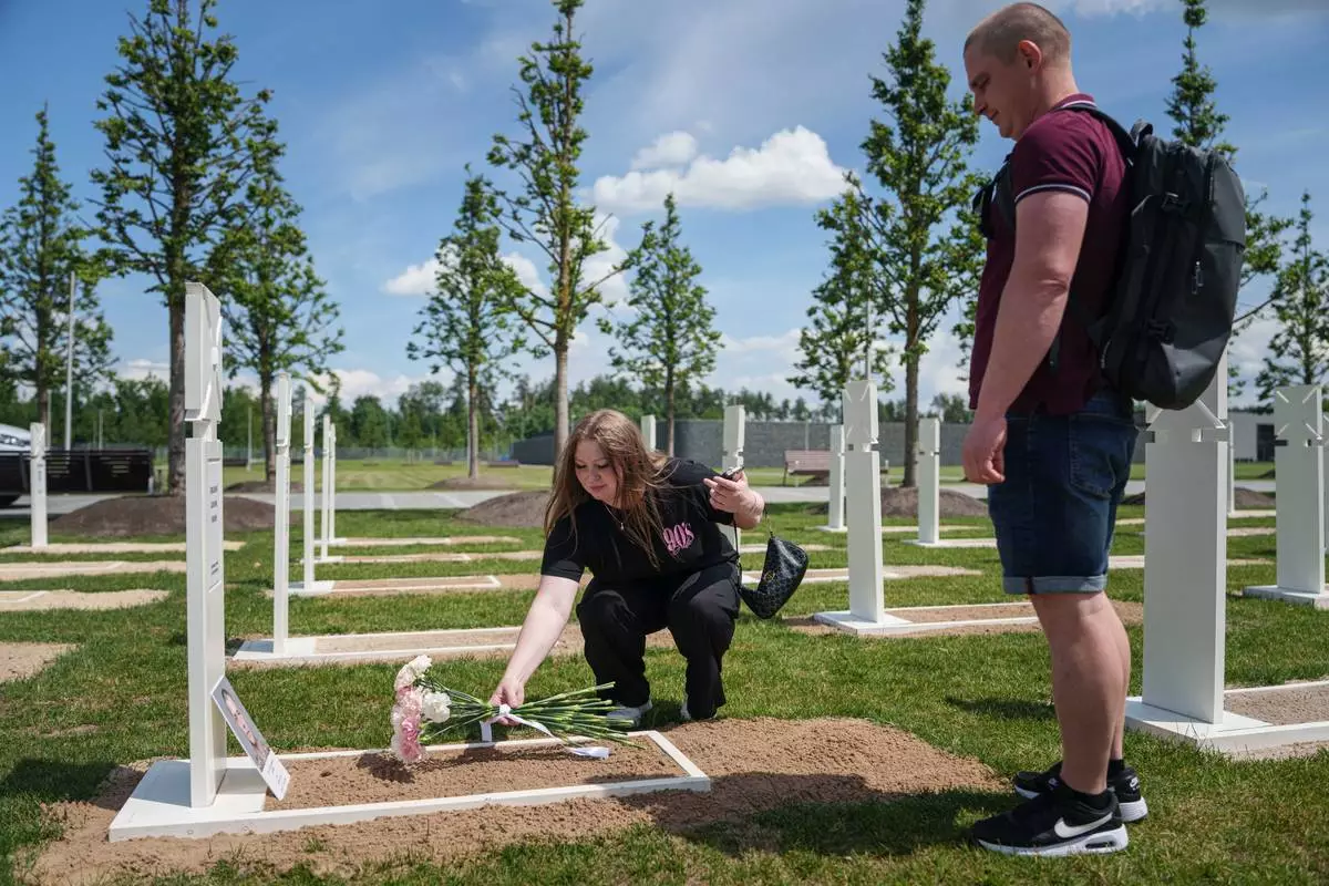 Stanislav and Oleksandra Yalynych lay flowers on the grave of their father Ihor Yalynych, a Ukrainian soldier who has been missed since 2022, at the military cemetery near Kyiv, Ukraine, Wednesday, June 17, 2026. (AP Photo/Evgeniy Maloletka)