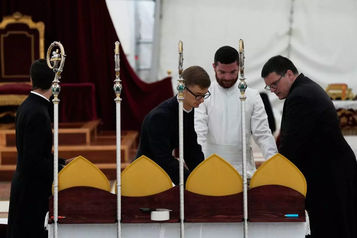 Priests prepare miters and pastoral staffs before the start of a consecration ceremony for four new bishops, in a tent set up outside the Society of St. Pius X seminary, in Econe, Switzerland, Wednesday, July 1, 2026. (AP Photo/Baz Ratner)