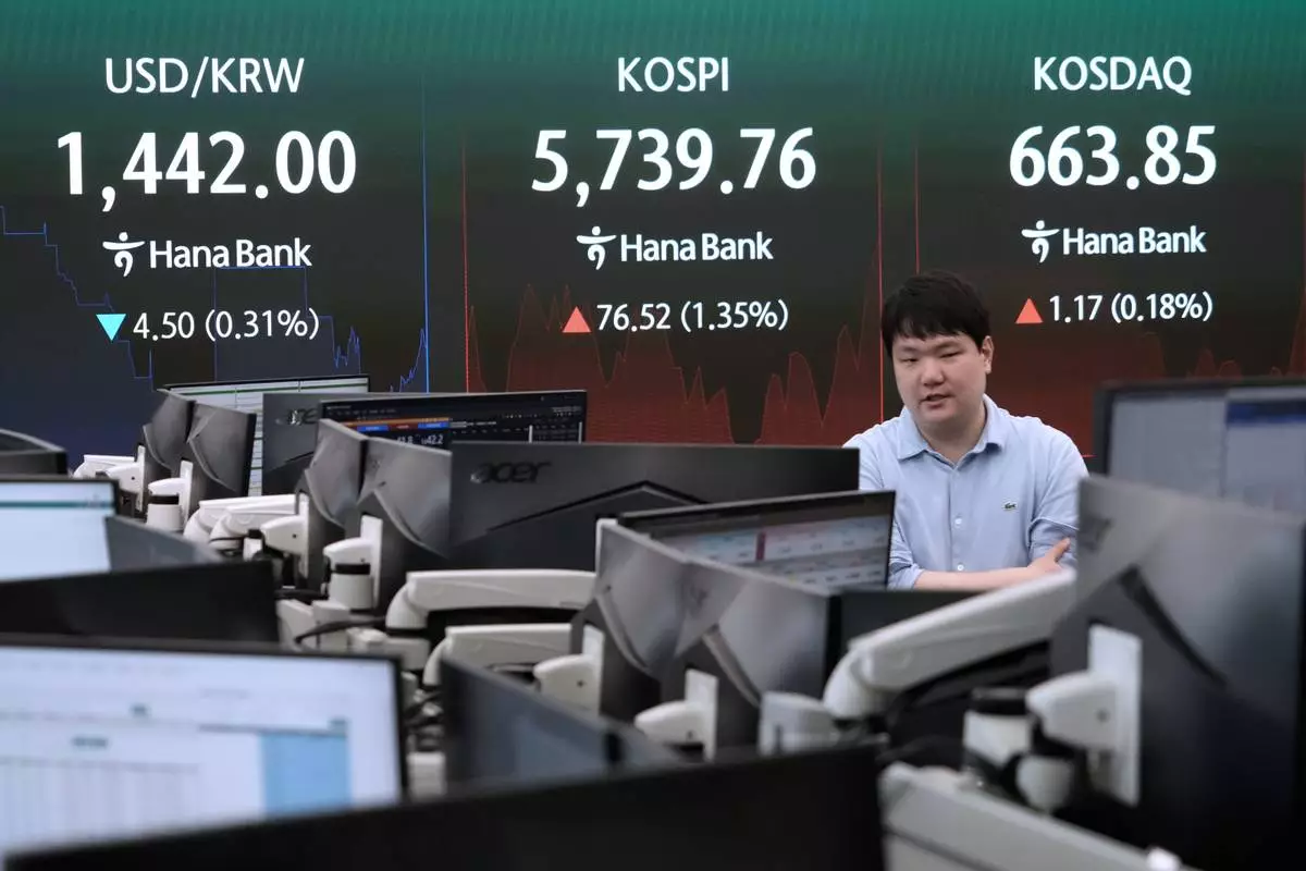 A currency trader passes by a screen showing the Korea Composite Stock Price Index (KOSPI) and the foreign exchange rate between U.S. dollar and South Korean won at the foreign exchange dealing room of the Hana Bank headquarters in Seoul, South Korea, Thursday, July 30, 2026. (AP Photo/Ahn Young-joon)