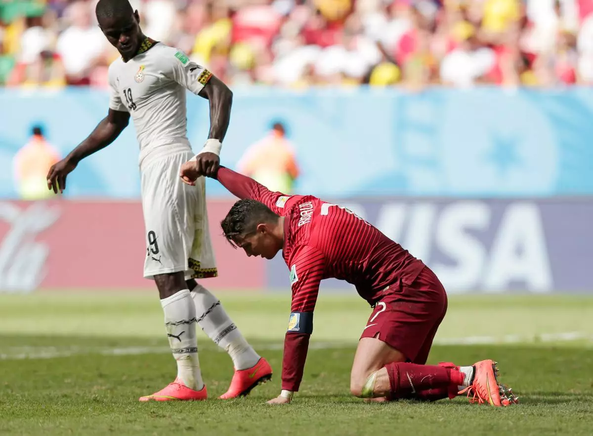 FILE - Ghana's Jonathan Mensah helps Portugal's Cristiano Ronaldo get up after he missed a chance to score during the group G World Cup soccer match in Brasilia, Brazil, June 26, 2014. (AP Photo/Marcio Jose Sanchez, File)