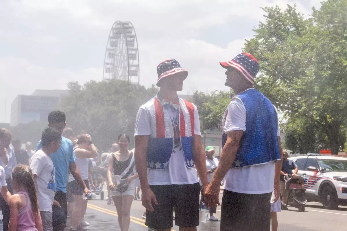 Attendees cool off in mist at the Great American State Fair on the National Mall, Friday, July 3, 2026, in Washington. (AP Photo/Allison Robbert)