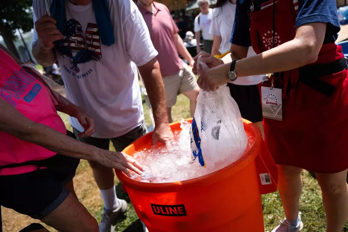 Attendees dip their hands in ice water at the Great American State Fair on the National Mall, Friday, July 3, 2026, in Washington. (AP Photo/Allison Robbert)