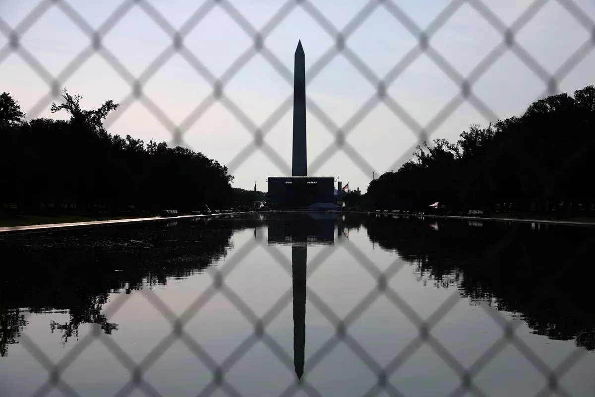 The Washington Monument, reflected in the Lincoln Memorial Reflecting Pool, is seen behind fencing, Tuesday, June 30, 2026, in Washington. (AP Photo/Rahmat Gul)