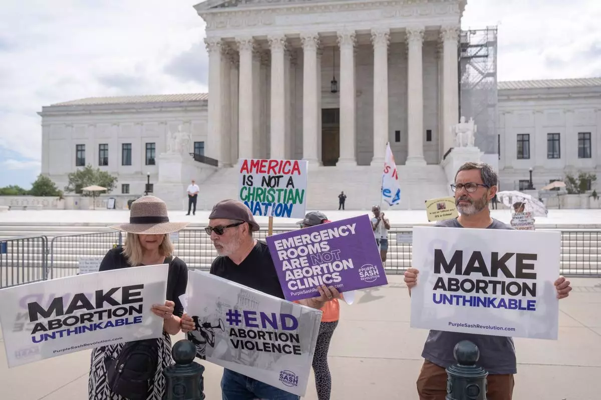 FILE - Katie Mahoney, left, and Rev. Patrick Mahoney, chief strategy officer for Stanton Healthcare, an Idaho-based pregnancy center that does not provide abortions, read the text of a Supreme Court decision outside the Supreme Court, June 27, 2024, in Washington. (AP Photo/Mark Schiefelbein, File)