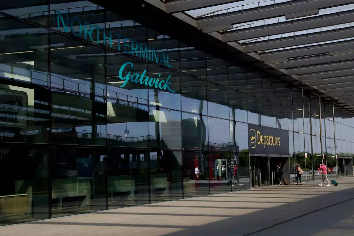 FILE - Passengers walk into the Departures entrance at the North Terminal of Gatwick Airport near Crawley, just south of London, on July 22, 2020. (AP Photo/Matt Dunham, File)