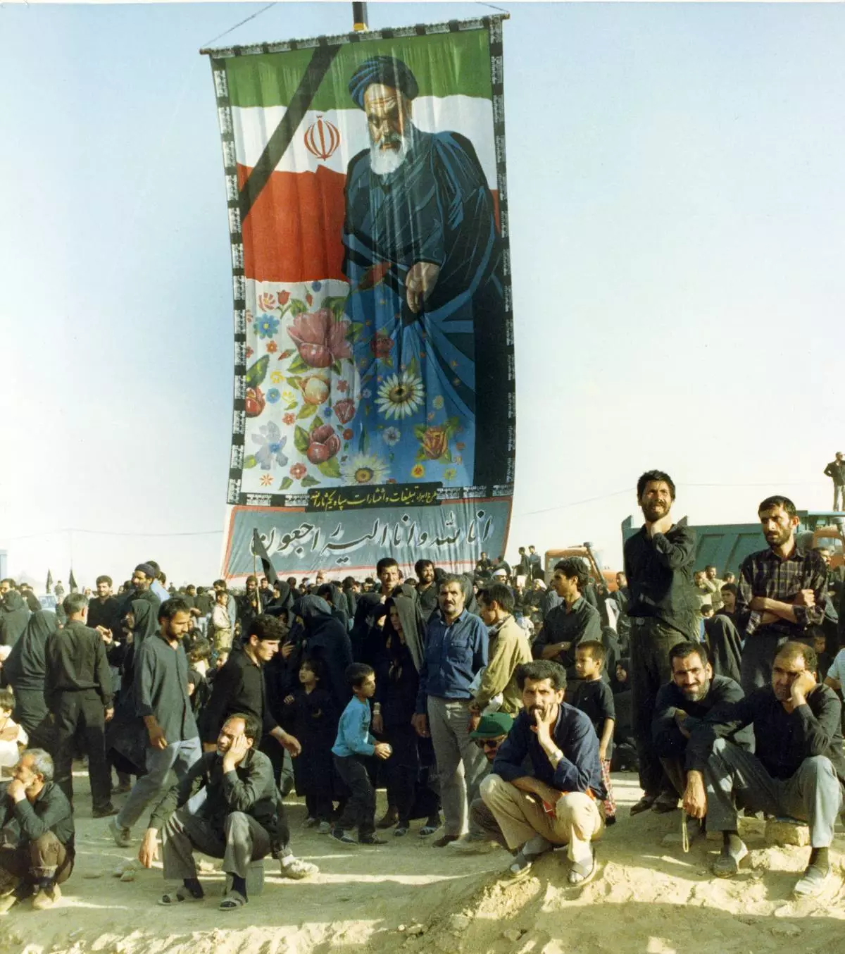 FILE - Mourners crowd around a huge banner with a picture of the late Ayatollah Khomeini at a cemetery in Beheshte e Zahra, some 70 kms from Tehran, Iran, June 11, 1989. (AP Photo/Heribert Proepper, File)