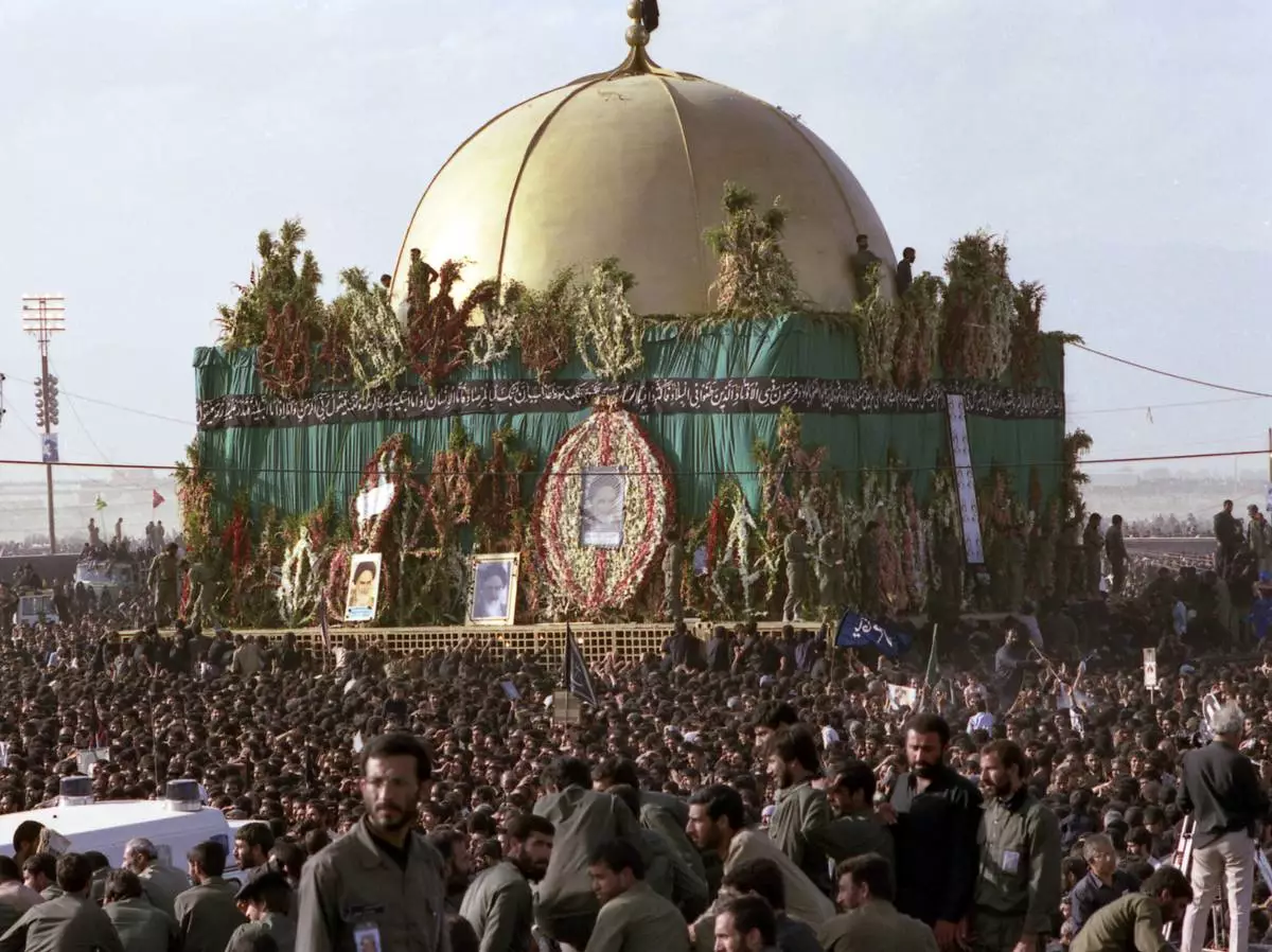 FILE- Thousands of mourners crowd around the grave of the late Ayatollah Khomeini at the cemetery in Beheshte e Zahra, some 70 kms from Tehran, Iran, June 11, 1989. (AP Photo/Heribert Proepper, File)