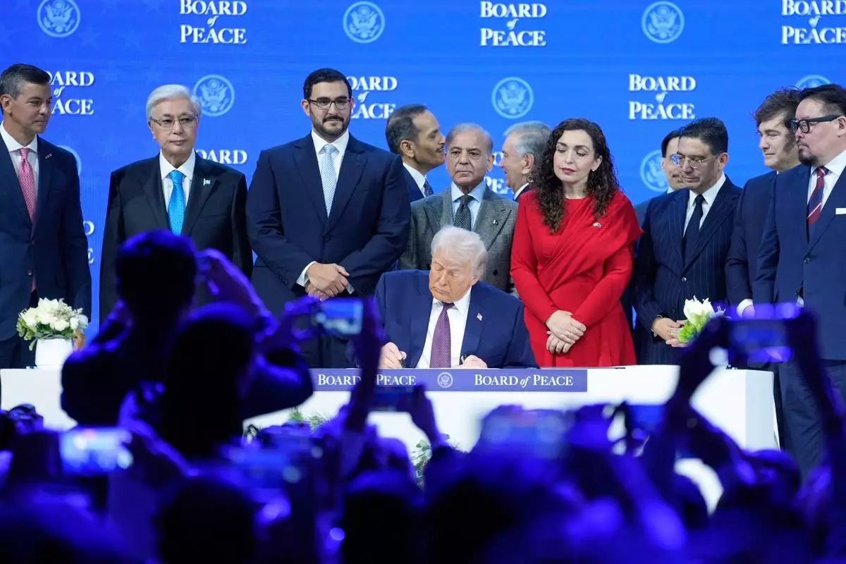 FILE - President Donald Trump signs the charter of his Board of Peace initiative at the Annual Meeting of the World Economic Forum in Davos, Switzerland, Jan. 22, 2026. (AP Photo/Markus Schreiber, File)