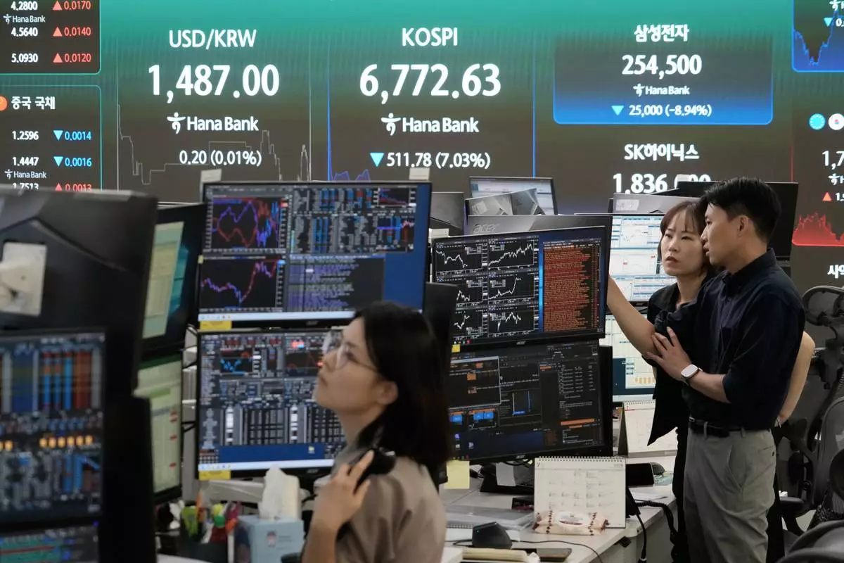 Currency traders work near a screen showing the Korea Composite Stock Price Index (KOSPI) and the foreign exchange rate between U.S. dollar and South Korean won at the foreign exchange dealing room of the Hana Bank headquarters in Seoul, South Korea, Thursday, July 16, 2026. (AP Photo/Ahn Young-joon)