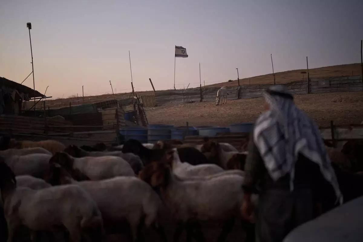 An Israeli flag, set up by settlers, waves beside a fence around a Palestinian compound's sheep pen at dusk in the northern Jordan Valley in the occupied West Bank, Tuesday, June 23, 2026.(AP Photo/Leo Correa)