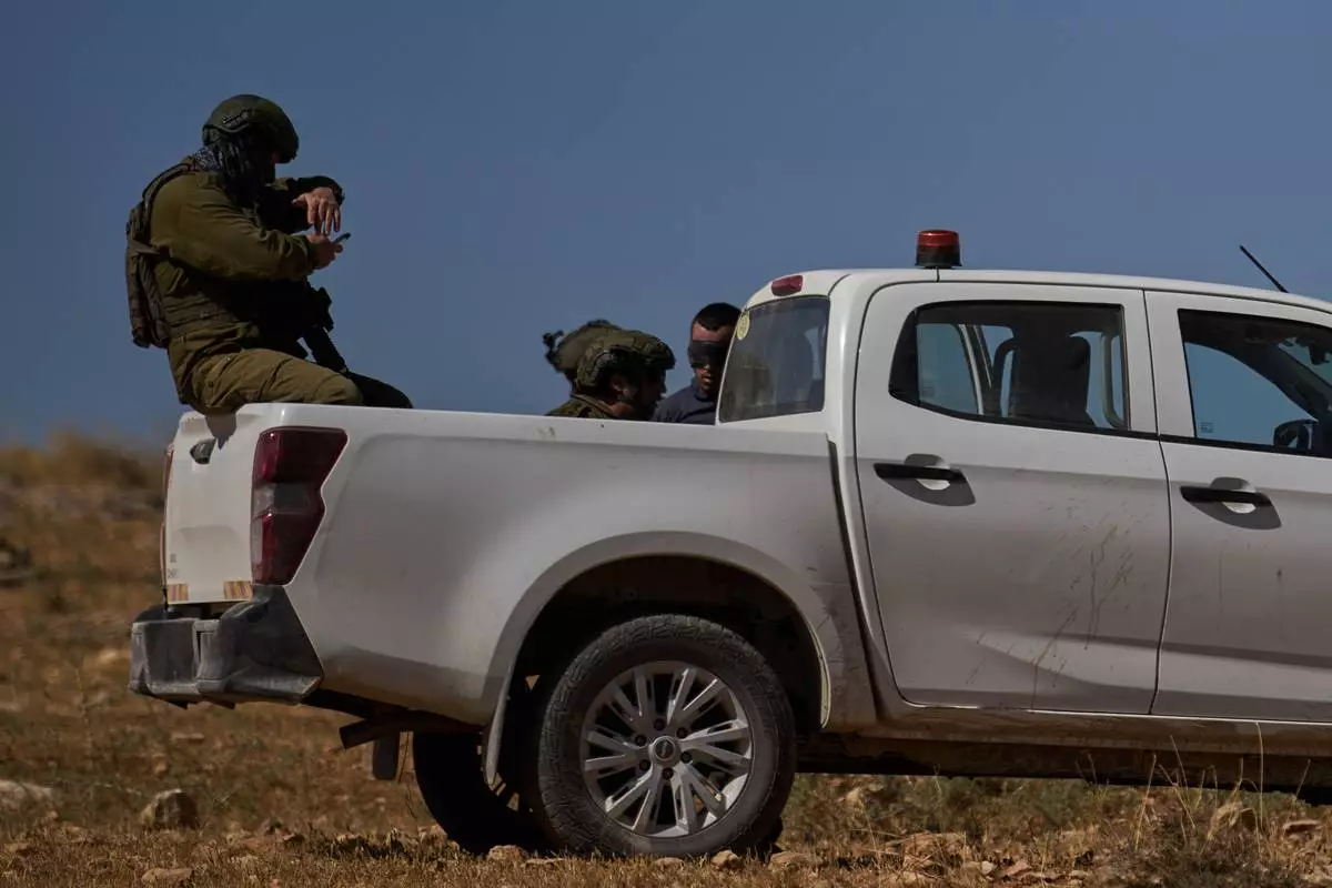 A blindfolded Palestinian is detained by Israeli soldiers after being accused by Israeli settlers of setting a field on fire near the West Bank village of Susya, in the Masafer Yatta region, Thursday, June 18, 2026.(AP Photo/Leo Correa)