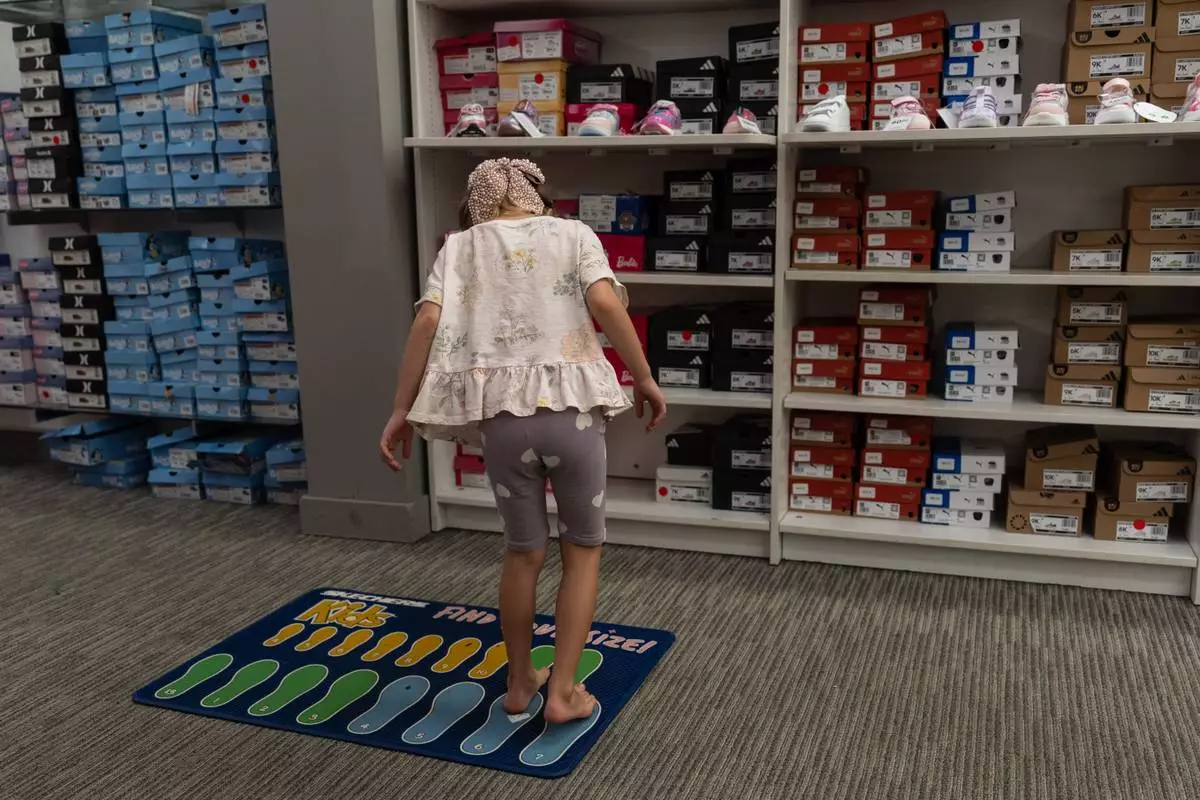Lola Lialina stands on a foot-measuring mat while shopping for shoes with her parents at a JCPenney store in Glendale, Calif., Tuesday, Aug. 11, 2026. (AP Photo/Jae C. Hong)