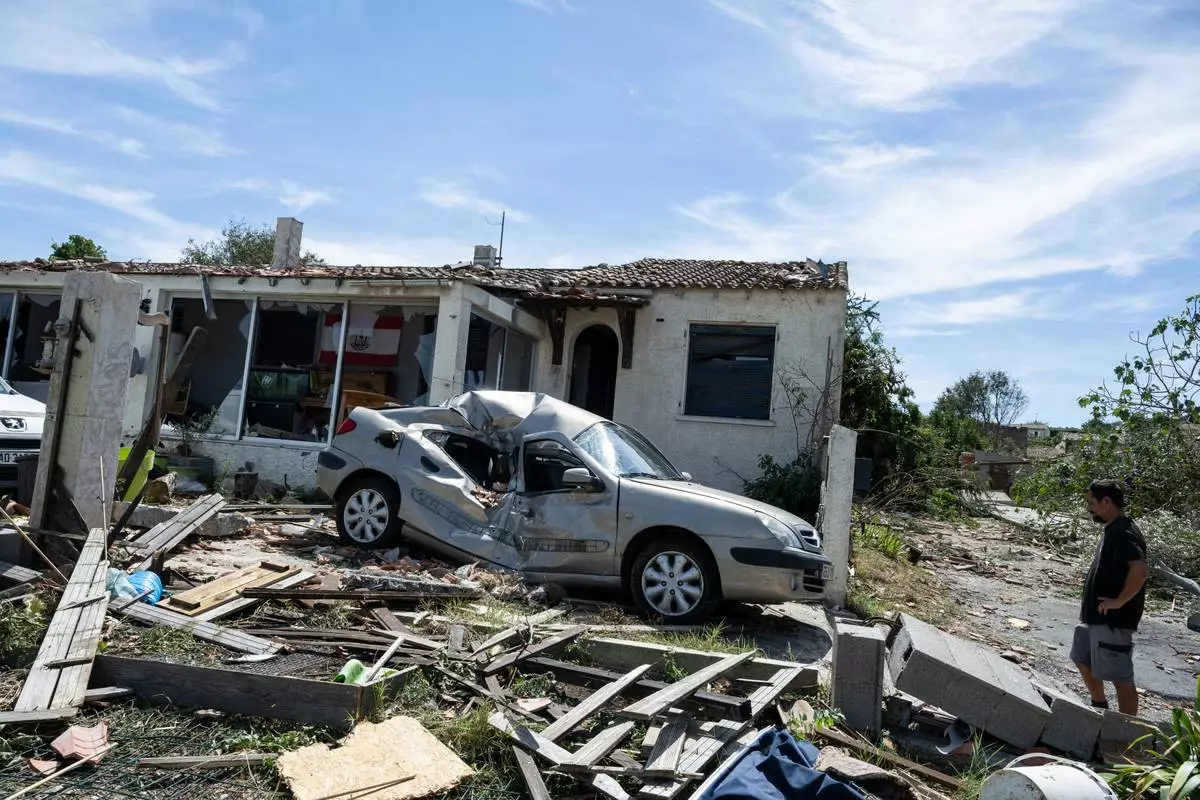 A resident stands outside a damaged home after a tornado ravaged the small village of Pomas in southern France, Tuesday Aug. 25, 2026. (AP Photo/Frederic Lancelot)