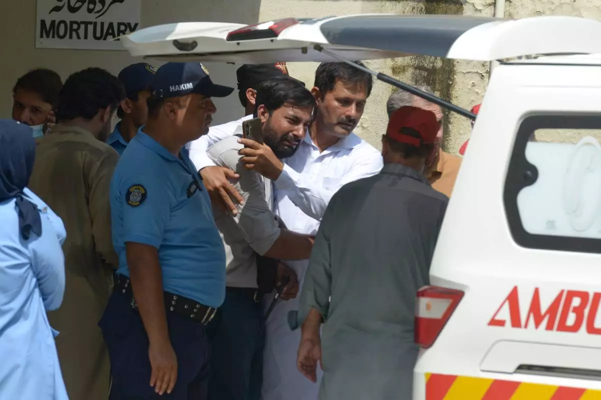 A father, center, of a victim in a fire is comforted as his child's coffin is carried outside a hospital in Islamabad, Pakistan, Wednesday, Aug. 26, 2026. (AP Photo/M.A. Sheik) CORRECTION: Corrects date/day